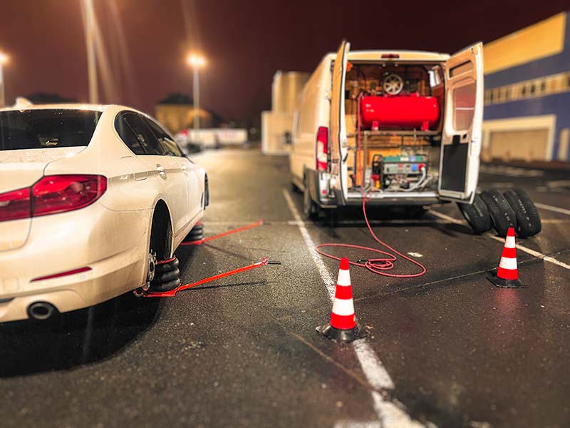 Mobilna wulkanizacja szczecin mobilna wymiana opon w białym samochodzie BMW wieczorem na parkingu sklepowym