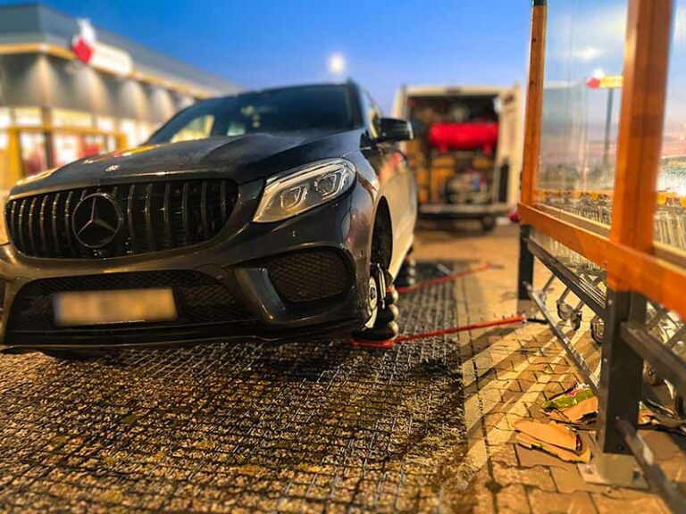 Mobilna wulkanizacja szczecin mobilna wymiana opon w czarnym samochodzie Mercedes SUV wieczorem na parkingu sklepowym